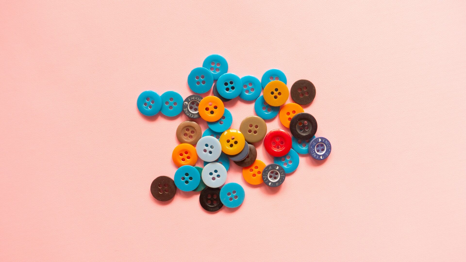 Bunte Knöpfe auf rosa Hintergrund